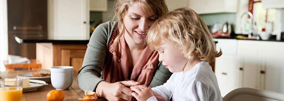 Mother and daughter having breakfast at kitchen table.